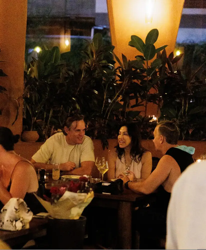 Friends sharing dinner at a long table in Jannah's garden