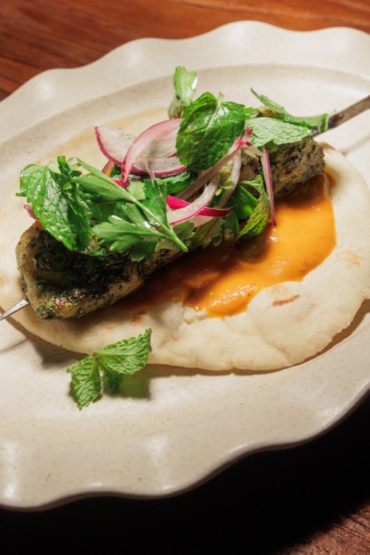 Fish skewer with charred harissa on flat bread