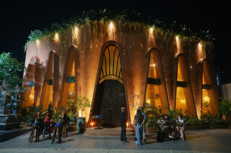Jannah's terracotta facade with lit arches at night